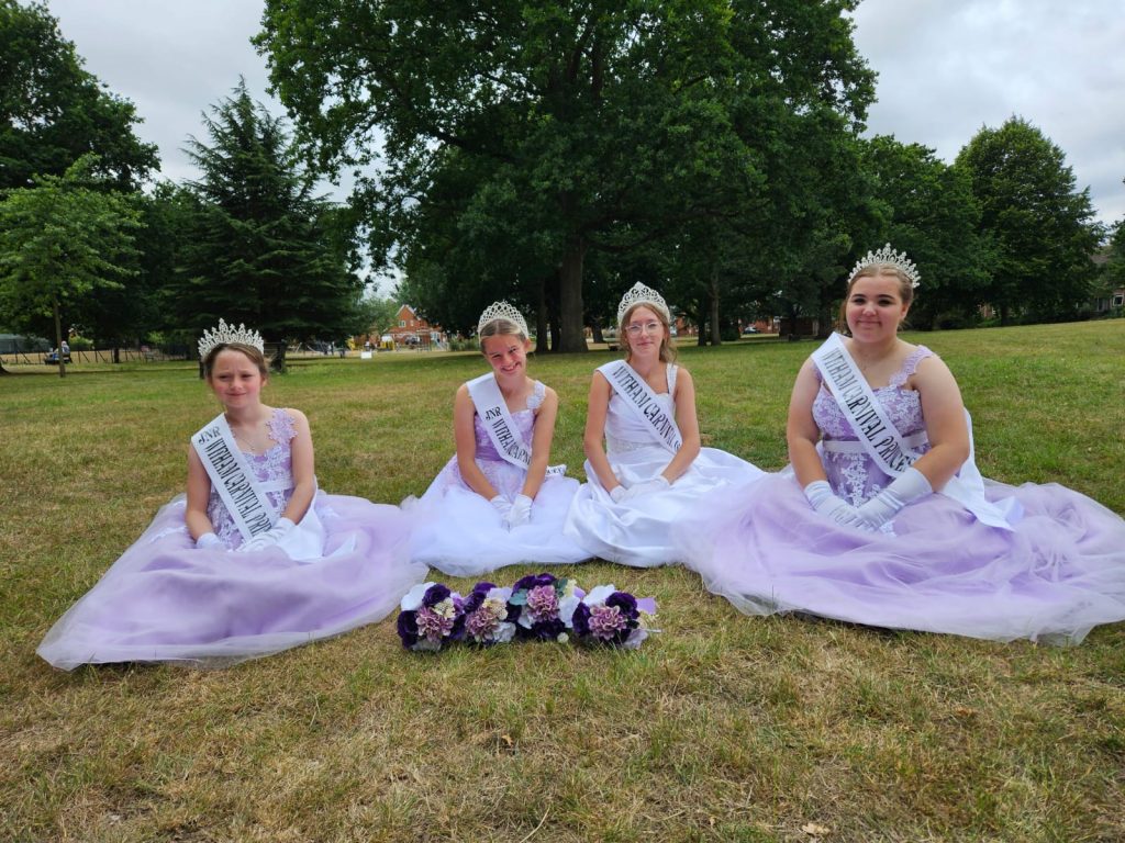 four girls in formal dresses sitting on the grass